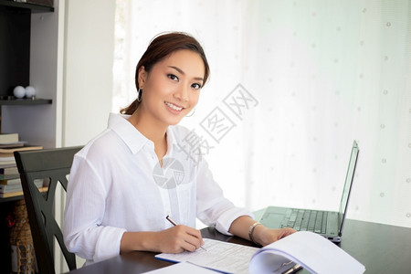 在职的公司使用笔记本亚洲商业妇女为工作而笑高兴坐着图片