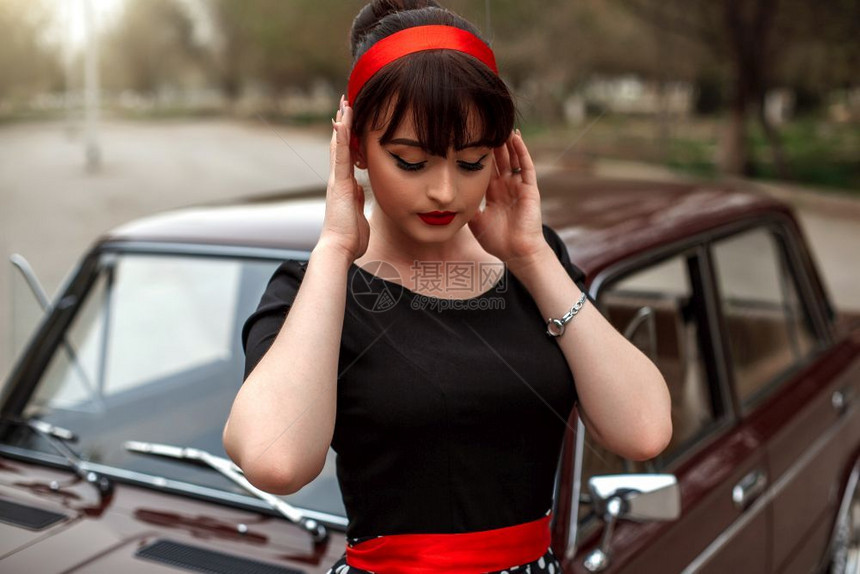 化妆品时尚身着黑色旧礼服在一辆车旁边摆姿势的高加索美丽年轻女孩肖像时髦的图片
