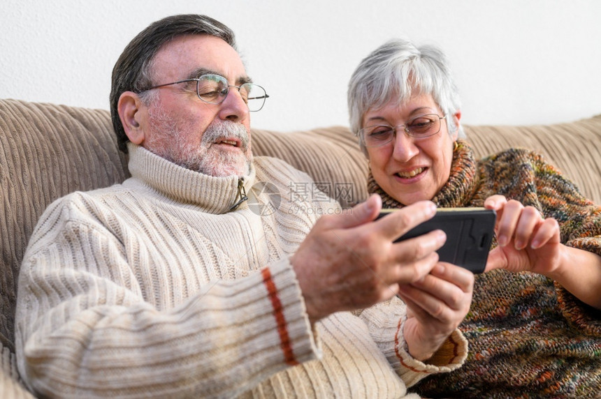 移动的学习数字Covid19待在家里快乐的退休老年夫妇用手机进行家庭视频通话社交距离积极的表达Covid19快乐的退休老年夫妇积图片