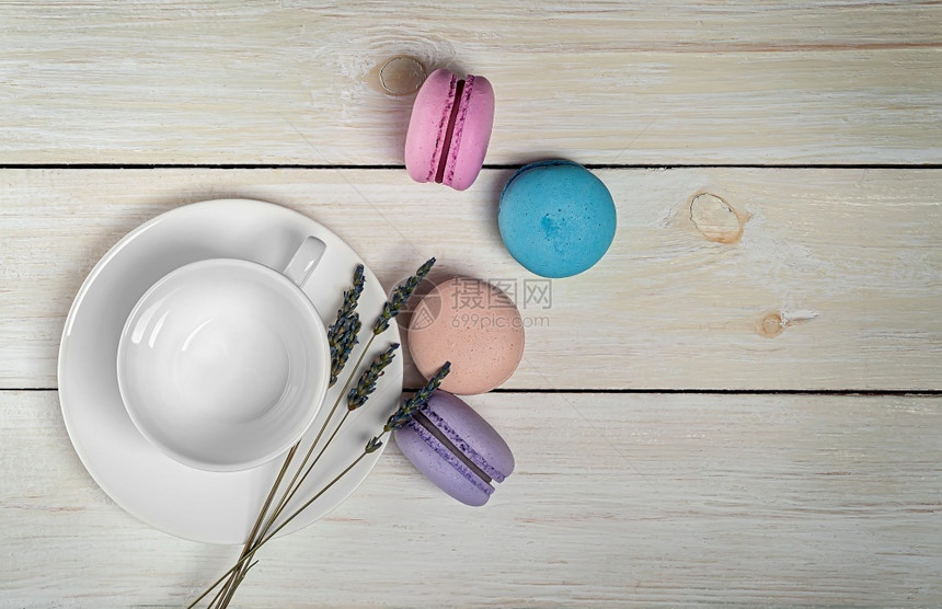 白色咖啡杯附近的多彩马卡龙和木制桌面的白咖啡杯和熏衣草顶部视图咖啡杯顶端的Macarons传统的奶油颜色图片