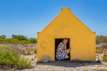 荷兰语建造假期妇女进入Bonaire海滩的黄色奴隶屋图片
