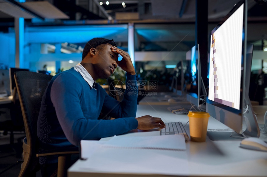 睡在桌子上边的经理人睡在晚间办公室生活方式在笔记本电脑上的男人背景黑暗内深处的人睡在桌边现代工作场所经理人晚间办公室生活方式自由图片