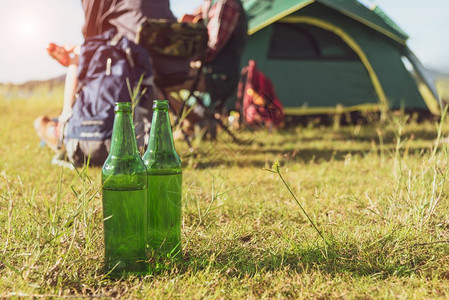 在野外露营时草地上紧贴啤酒瓶的假日和节概念冒险和户外主题人们野营假期图片