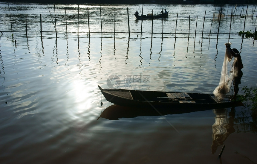 轮船上的渔民站立在排船上捡起网修理捕鱼作业以在洪水季节的清晨在河上捕捞鱼轮廓抓住捕捉图片