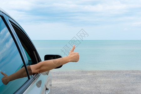 夏天假期自然欢乐女人在明亮的一天从停在海上的汽车举起双臂图片