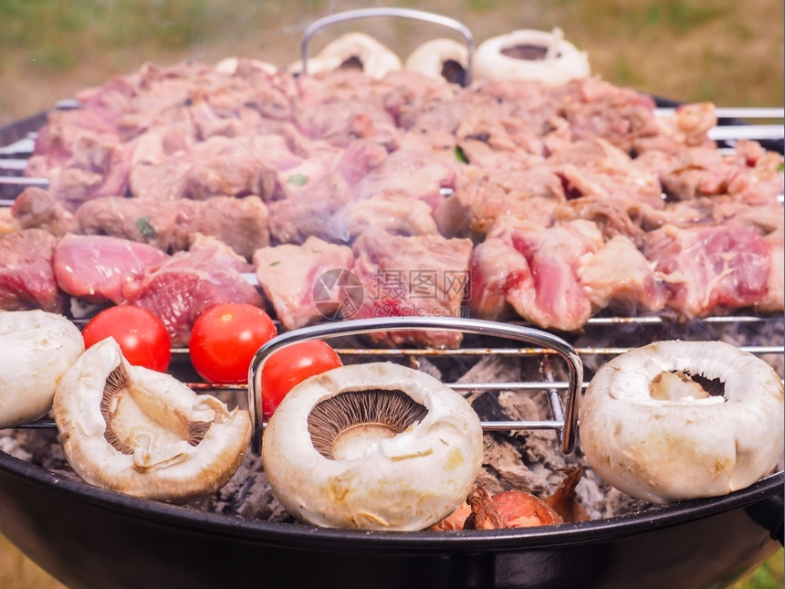 热的蘑菇肉串黑圆木炭烧烤室外的黑圆形木炭烤肉图片