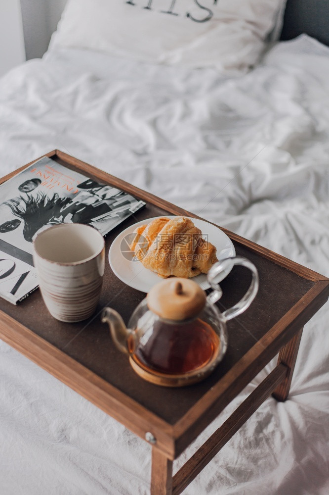 冬天一种早餐在床上托盘加咖啡茶叶和牛角面包的咖啡茶和羊角面包放在床上舒适图片