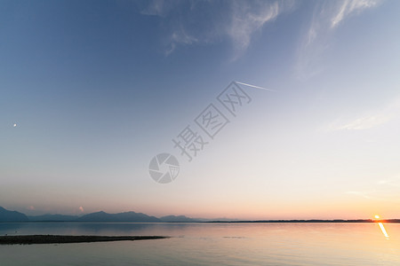 和平与安宁在巴伐利亚湖中日落与月和太阳同时交汇的天文结合湖边和平蓝色的背景