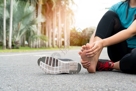 人们肿亚洲女在锻炼跑步运动和损伤概念时按摩疼痛的脚赛跑者图片