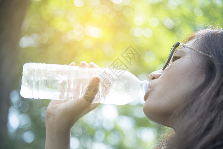 保持美丽的女孩喝水从瓶子的自然绿色夏天图片