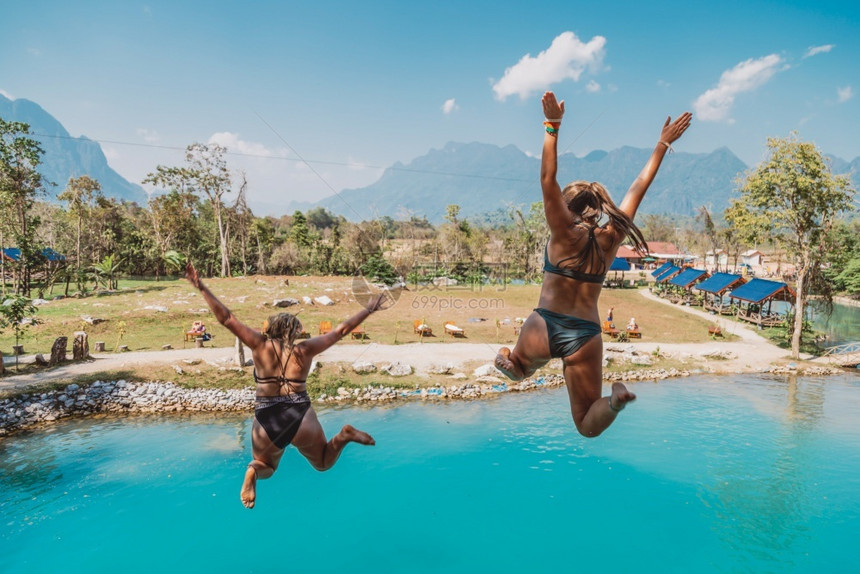 快乐的假期热带两个女孩跳入水中图片