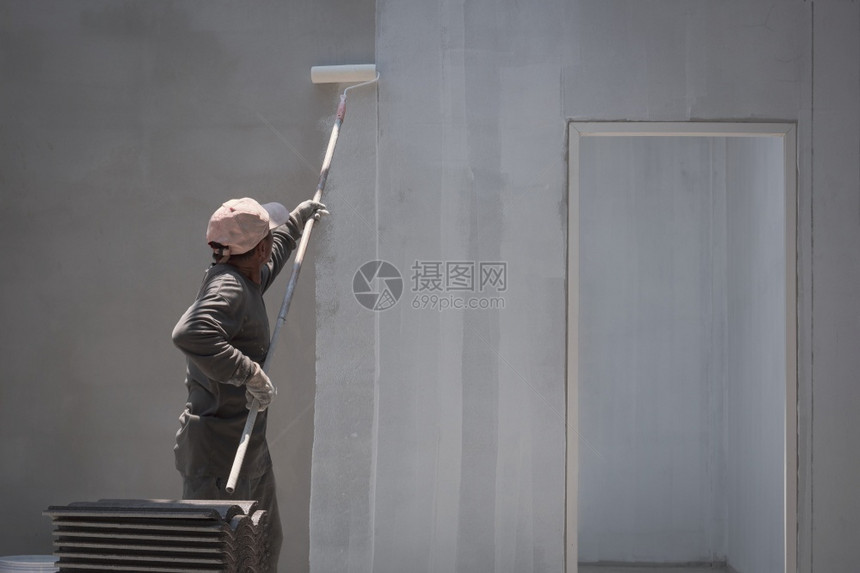 处理结构体改进亚洲建筑工人的后侧观他们使用长柄滚圈刷在房屋建筑工地内水泥墙背景上涂白刻底漆入门粉刷图片