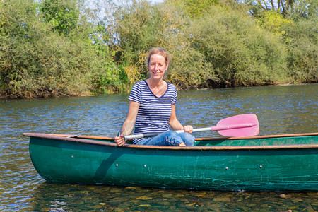 女坐着白种人在德国河水上冒着独木舟划桨的白种女人图片