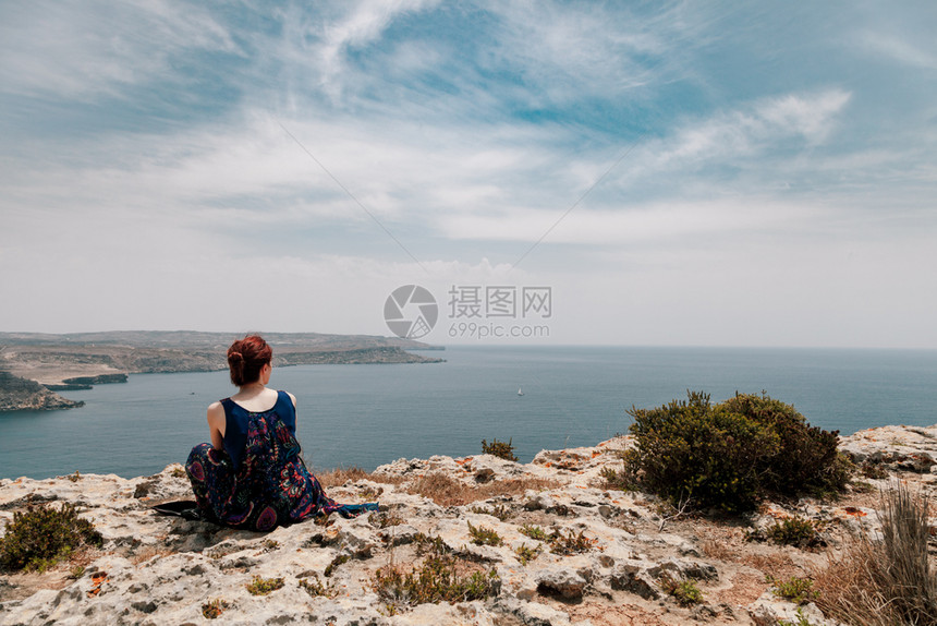 危险情感坐在悬崖边缘的红发年轻女人身着顶骨向远海看髻图片