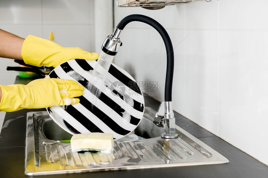 在家工作液体厨房洗碗池里用黄色橡胶手套洗碗盘贴近人手锅图片