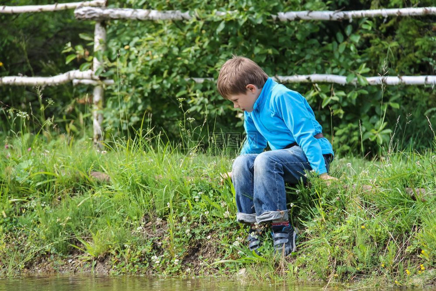 叶子玩坐在湖边的英俊男孩爬坡道图片