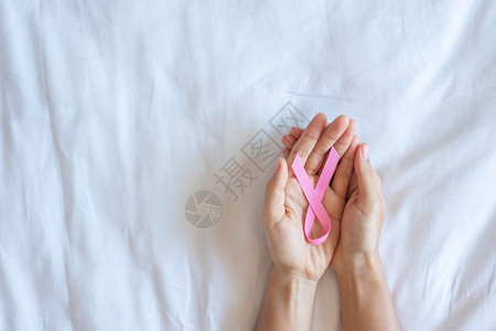 女士手握红丝带预防癌症概念图片