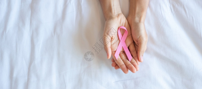 手捧粉色丝带预防乳腺癌概念图片