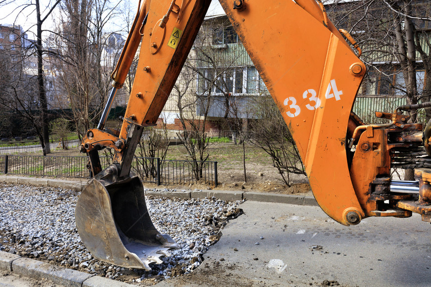 在修理人行道Bucket时重路挖土机及其水桶和蓬隆的重型挖土机瓦砾在修理人行道时用大巴基特和重型挖土机箭击打修复力量街道图片