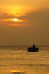 人类和谐洋上美丽的风景日落时鱼人站立在圆船上划日落时太阳下山日落时天光亮黄越南背景图片