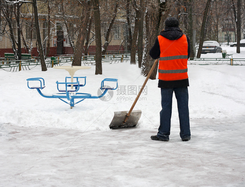 庭院冬季在游乐场除雪一个人拿着铲子从铁轨上扫雪深的树木图片