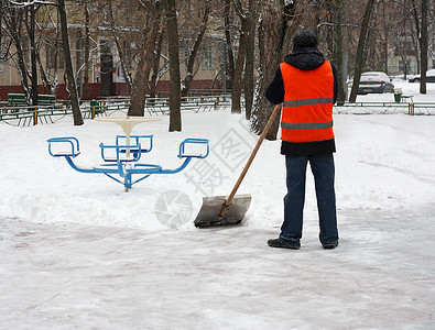 庭院冬季在游乐场除雪一个人拿着铲子从铁轨上扫雪深的树木图片