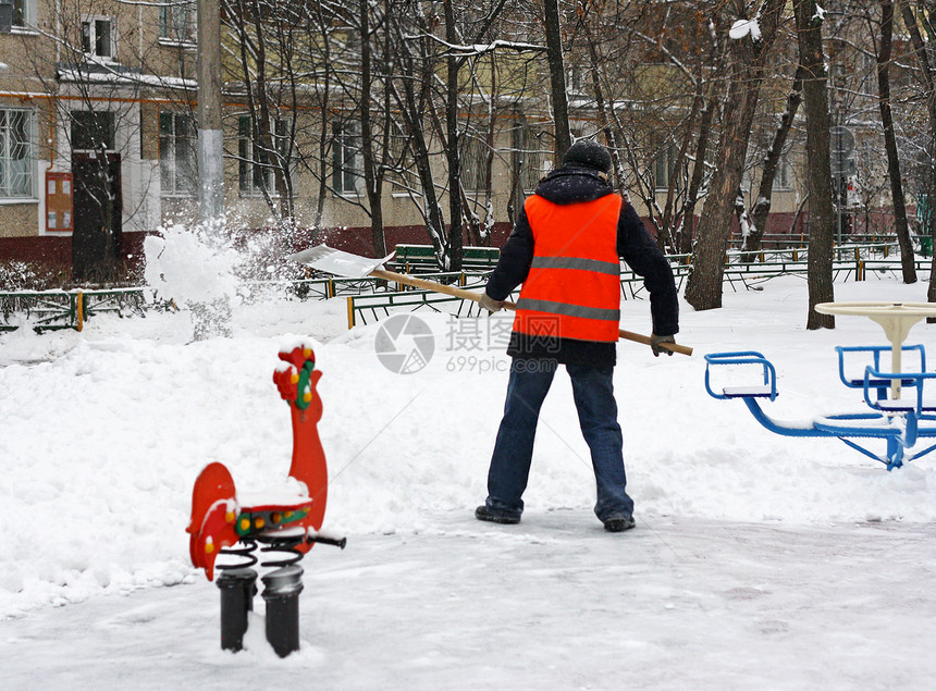 塑料单身的冬季在游乐场除雪一个人拿着铲子从铁轨上扫雪干净的图片