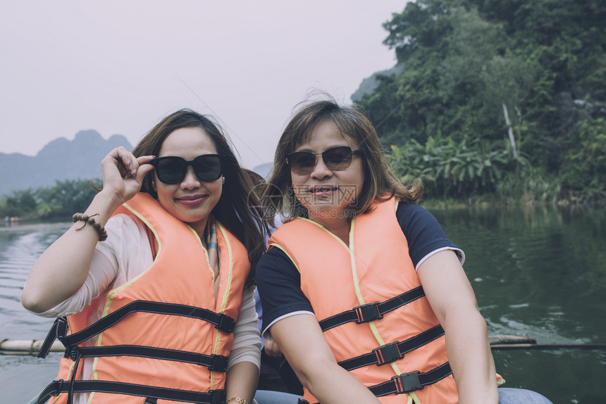 友谊运河风景两名亚裔女游客身着救生衣帆船在宁宾河中搭乘最受欢迎的交通目地vietnam图片