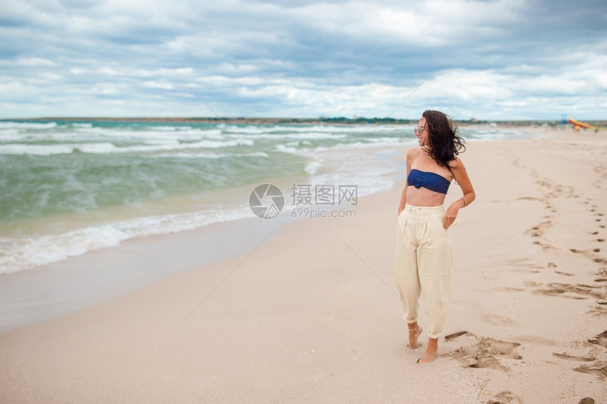 海滩上的年轻美女在风雨多云的天气中暴风雨的海滩上年轻美女享受幸福年轻的图片