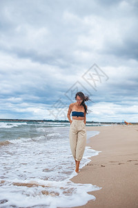 海滩上的年轻美女在风雨多云的天气中暴风雨的海滩上年轻美女保持户外士图片