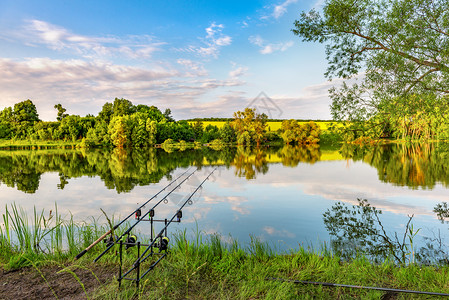 池塘夏季日出在河上捕捞鲤鱼的渔船棒在河上捕鱼的渔竿外部地平线图片