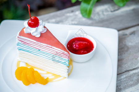 彩虹crepe蛋糕和樱桃木桌背景上加草莓酱美味的绿色红图片