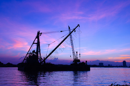 施工货运现代的在河上漂浮Silhouette建筑工地反省日落概念图片