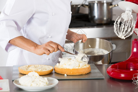 乳脂制造抹刀厨师装饰一个美味的蛋糕加奶油图片