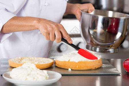 厨师装饰一个美味的蛋糕加奶油工作机器拂图片