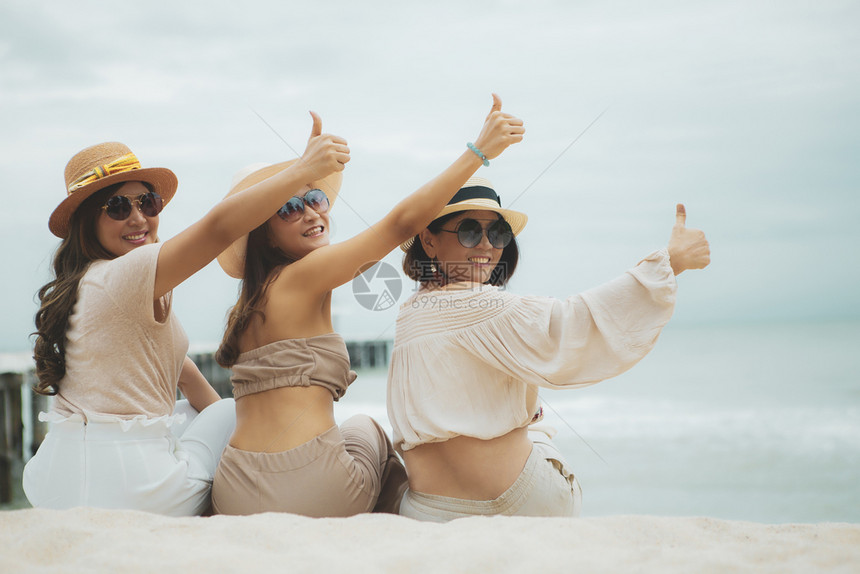 三位身戴草帽的女士坐在度假沙滩上图片