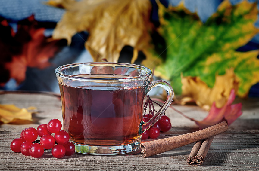 荚um黑色的棕茶杯羊毛围巾草莓和香料放在生锈的木制桌布上一个透明的杯子和红树叶中的黑茶图片