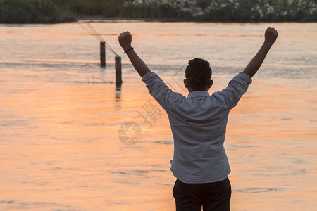 男生亚洲人举起手自由欣赏河上美丽的日落成功理念黎明蓝色的图片