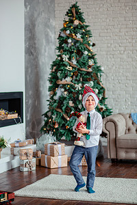 小男孩在圣诞树下打开礼物图片