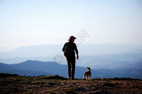 一个男人带着狗在山谷上方的悬崖男人带着狗在山谷上方的悬崖树棕色乡村图片