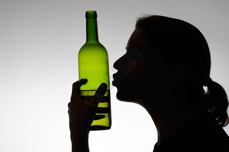 一个女人接吻葡萄酒瓶子的休眠酗过量女士图片