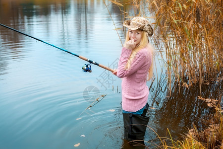 穿粉红色毛衣钓鱼的金发美女士照片池塘图片