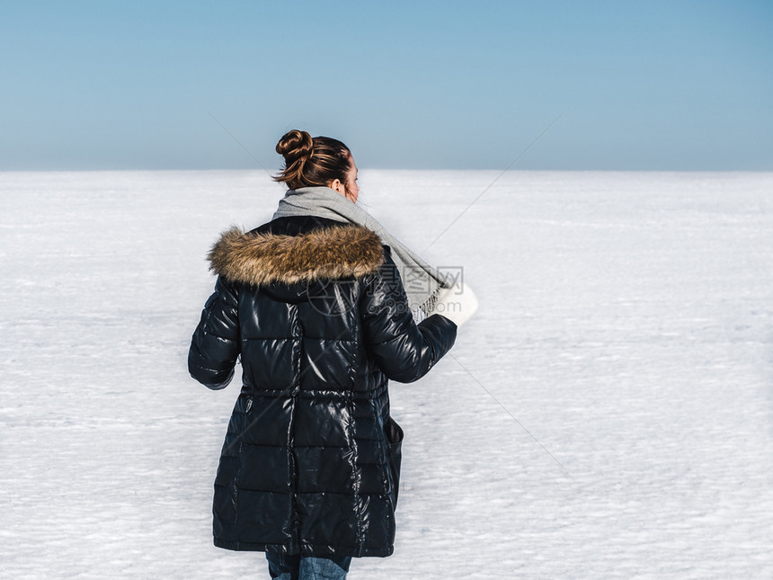 夹克黑发快乐年轻女在雪地的背景一个晴朗阳光明媚的一天幸福女在雪地背景新的图片