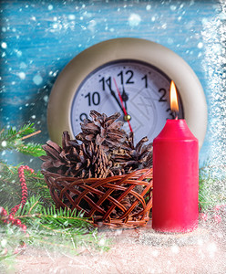 红蜡烛带锥子的篮和有年最后几分钟的手表下着雪霜季节圣诞图片