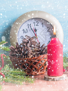 红蜡烛带锥子的篮和有年最后几分钟的手表下着雪花数字季节图片