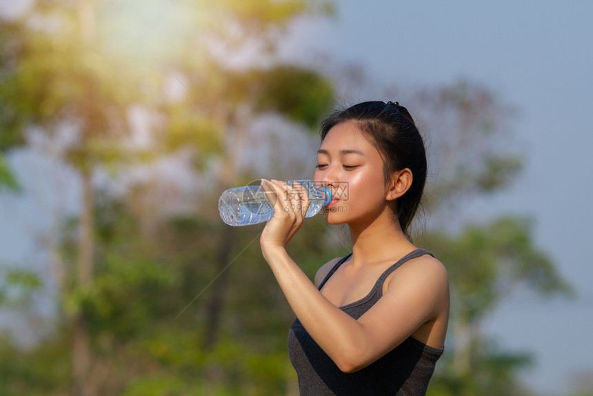 阳光明媚的天户外运动妇女作为体育田内子饮用水训练疲劳的亚洲人图片