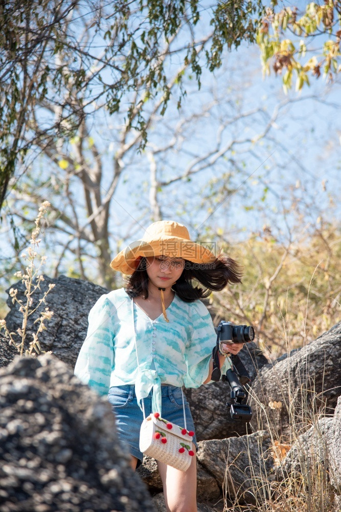 差距亚洲漂亮可爱的女子短牛仔裤穿着帽子在山上森林里徒步悬崖上有快乐和自由的情感在概念旅行积极生活方式度假克服生活障碍等方面女带着图片