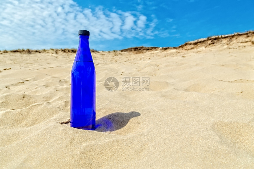 蓝水瓶直立地站在像沙漠一样干燥的黄沙中瓶子健康季节图片