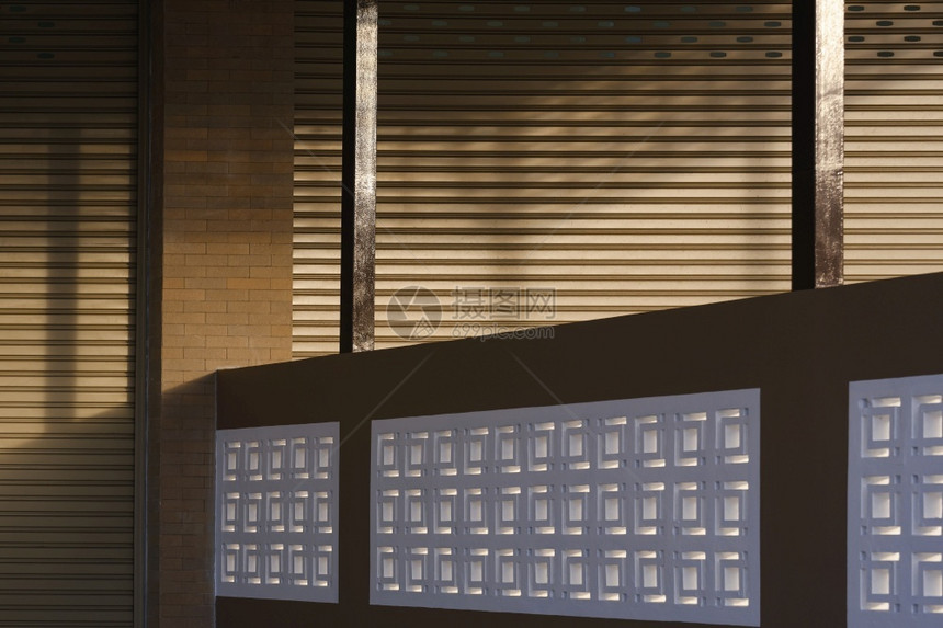 商业的滚轴砖夜间用水泥栅栏隔开商业大楼的滚锁门窗表面的阳光和阴影在夜间被水泥围栏隔开图片