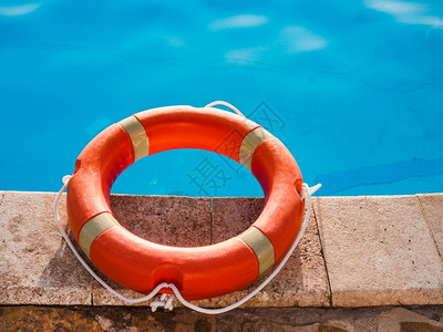 水池直接地帮助泳背景上的明亮橙色救生圈泳池背景上的安全护理和援助概念图片